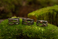 Ladda upp bild i Galleri visare, Udstillet på en seng af frodig grøn mos er tre indviklet designede mørke metalringe med naturinspirerede mønstre, hver prydet med små ædelsten. Disse ringe, kaldet Fingerring - Eryn Design - Moria (Simpel), fremviser en organisk, sammenflettet struktur, der ligner kviste eller grene. De er perfekte eksempler på håndlavede smykker.