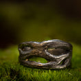 Ladda upp bild i Galleri visare, Et nærbillede af en rustik, sølvfarvet ring på en bund af grønt mos. Denne fingerring - Eryn Design - Moria (Simpel) har et organisk, sammenflettet design med uregelmæssige åbninger, hvilket giver den et naturligt og robust udseende. Baggrunden er sløret, hvilket understreger teksturen og detaljerne i dette stykke dansk design håndlavede smykker.
