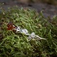 Ladda upp bild i Galleri visare, Rosebrosch med rav i 925s silver, formad som en stilk med blad, med äkta rav som liknar en blomknopp på grön mossa. Hantverket efterliknar en naturlig ros.