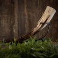 Ladda upp bild i Galleri visare, En poleret Drikkehorn Basic uden holder hviler vandret på et metalstativ. Hornet har nuancer af creme, brun og sort, sat mod en rustik træbaggrund. Grønt er synligt i forgrunden og tilføjer et strejf af natur, der minder om gammel vikingemarkeder.