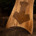 Ladda upp bild i Galleri visare, Nærbillede af bunden af et træstolsarmlæn, med et indgraveret og dekoreret design, der minder om Thors Hammer fra nordisk mytologi. Træet har en poleret finish, og messingnitter fremhæver vikingeudsmykningen smukt, ligesom det håndværk, der ses på Drikkehorn Raw med Thors Hammer Holder.