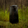 Ladda upp bild i Galleri visare, Et Vikingekrus Thors Hammer Horn (600-800 ml) med et indgraveret design, der ligner Thors Hammer, hviler på en plet græs, med en forvitret trævæg i baggrunden.