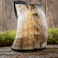 Ladda upp bild i Galleri visare, Vikingekrus Yggdrasil Horn, et drikkekar med træhorn med et udskåret Yggdrasil trædesign, vises opretstående på en stenoverflade. Mos og en forvitret træbaggrund fremhæver de rustikke omgivelser. Denne 600-800 ml, vikinge-inspirerede krus fremviser naturlige, jordnære nuancer og indviklet håndværk.