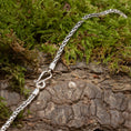 Ladda upp bild i Galleri visare, Et nærbillede af Halskæden ByKila Drageben 3mm 925s Sølv-kædearmbånd med et indviklet design og krogspænde, lagt på en struktureret træbark med grønt mos omkring sig.