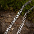 Ladda upp bild i Galleri visare, Nærbillede af to Halskæde Bismark 5,8mm 925s Sølv halskæder liggende på en struktureret træoverflade med grønt mos i baggrunden. De sammenlåsende led reflekterer lyset, fremhæver deres polerede finish og skaber et råt udtryk, der står i smuk kontrast til de naturlige elementer.