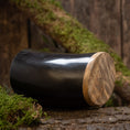Ladda upp bild i Galleri visare, En polerad svart dricksglas Horn Plain (500 ml) med en slät träbotten vilar på en rustik yta omgiven av grönska och träbark. Bakgrunden av träplankor framhäver den naturliga och jordnära känslan.