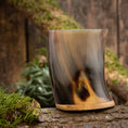 Ladda upp bild i Galleri visare, Ett polerat dricksglas Horn Plain (500 ml) med böjd design och träbotten står på en mossbelagd trästam. Bakgrunden visar en rustik träyta, delvis prydd med grön mossa och löv.