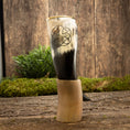 Ladda upp bild i Galleri visare, En dekorativ Drikkehorn Templar med et udskåret pentagram-symbol vises opretstående på en rustik træoverflade. Grønt løv og en trækulisse danner en naturlig ramme om det polerede bøffelhorn, der minder om vikingemarkeder.