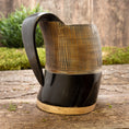 Ladda upp bild i Galleri visare, Et håndlavet Vikingekrus Bark Horn (600-800ml) med en poleret mørkebrun top og en lysebrun bund sidder på en rustik træoverflade med grønt i baggrunden. Denne ølkrus har et glat, buet håndtag og lodrette riller langs den øverste halvdel for tekstur.