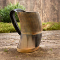 Ladda upp bild i Galleri visare, Et Vikingekrus Bark Horn (600-800ml) lavet af udskåret træ og poleret til en glat finish står på en rustik træoverflade. Hornet har lodrette riller langs kroppen, et sort håndtag og messingaccenter i bunden med grønt mos og træplader i baggrunden.