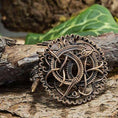 Indlæs billede i Gallery viewer, Broche Pitney Spænde Bronze, en autentisk bronze museumskopi, viser indviklede keltisk-inspirerede designs med detaljerede sammenvævede mønstre. Afbildet mod ru træbark og grønne blade i baggrunden har brochen en blanding af løkker og knuder inden for en cirkulær ramme, der minder om Urnestil-perioden.
