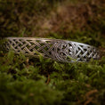 Indlæs billede i Gallery viewer, Armbånd Bangle Triskele 925s Sterling Sølv, der viser fint detaljerede keltiske knudedesigns, herunder en elegant triskele, hviler på en seng af frodig grøn mos. Armbåndets håndværk har kunstfærdige symmetriske mønstre, der fremkalder traditionelle kunstneriske stilarter.
