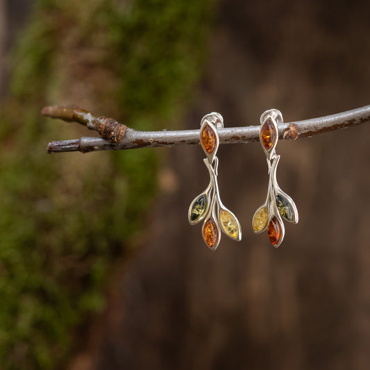 Eleganta hängörhängen Boroi i 925s silver med flerfärgade ädelstenar hänger från en kort trädgren. Varje örhänge har böjd silverdesign med fyra små marquiseslipade stenar i grönt, bärnsten och gult mot en suddig, jordig bakgrund.
