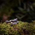 Indlæs billede i Gallery viewer, Et nærbillede af den udsøgt udformede Fingerring - Eryn Design - Treasure, lavet af 925'er Sterling Sølv og med en delikat guldkugle, hviler på levende grønt mos. Den let slørede baggrund fremhæver ringen og mosens naturlige tekstur.
